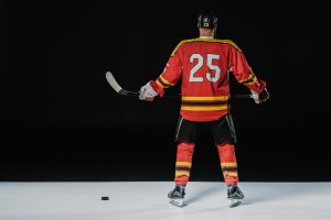 back view of professional ice hockey player holding hockey stick on black