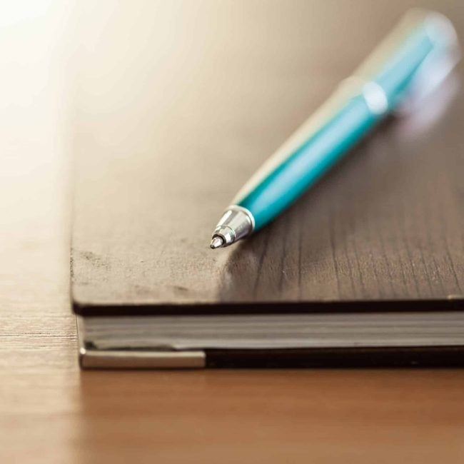 Blank note paper with pen on wood background